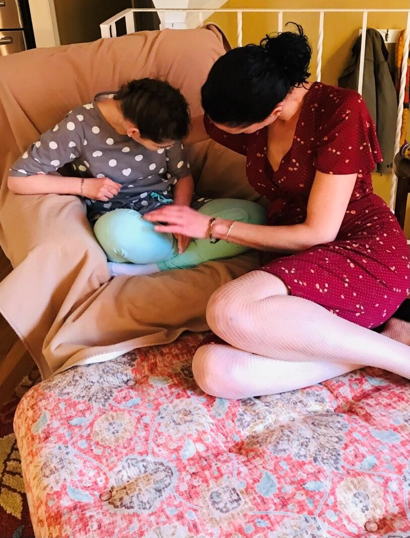 Image of Rachel Bancroft sitting on a chair providing care for an individual with complex needs