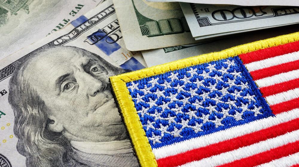 A photo of an American flag patch on top of hundred dollar bills