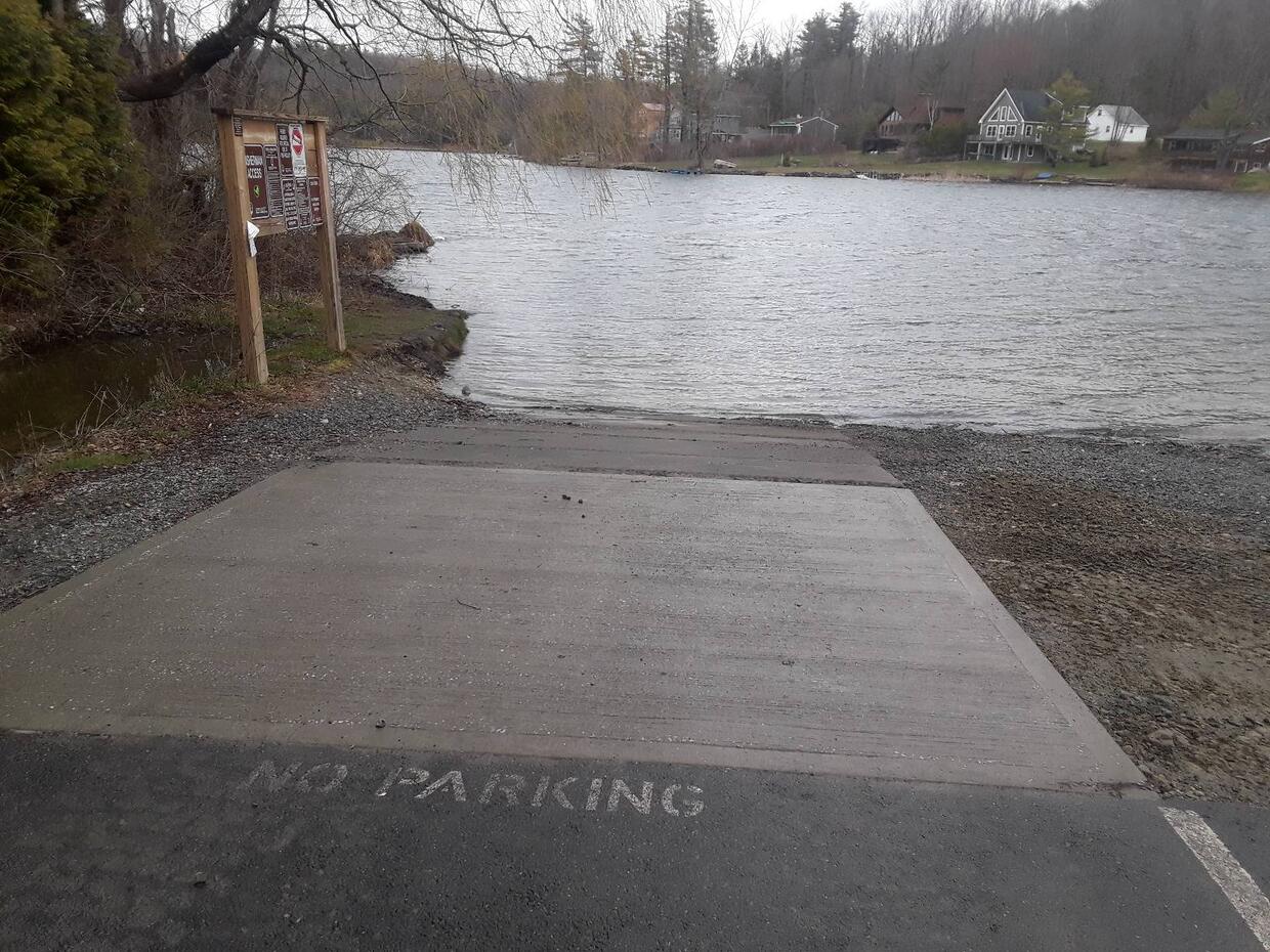 A small paved boat ramp leading out to the water on a cloudy day