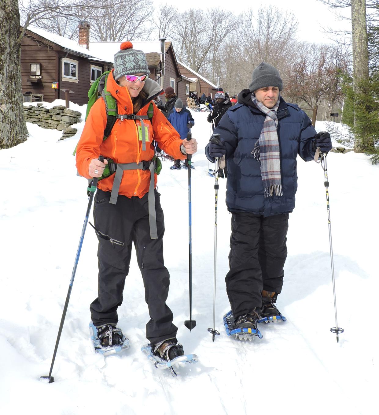 A group using snow shoes and ski poles sets off down a snowy hill.