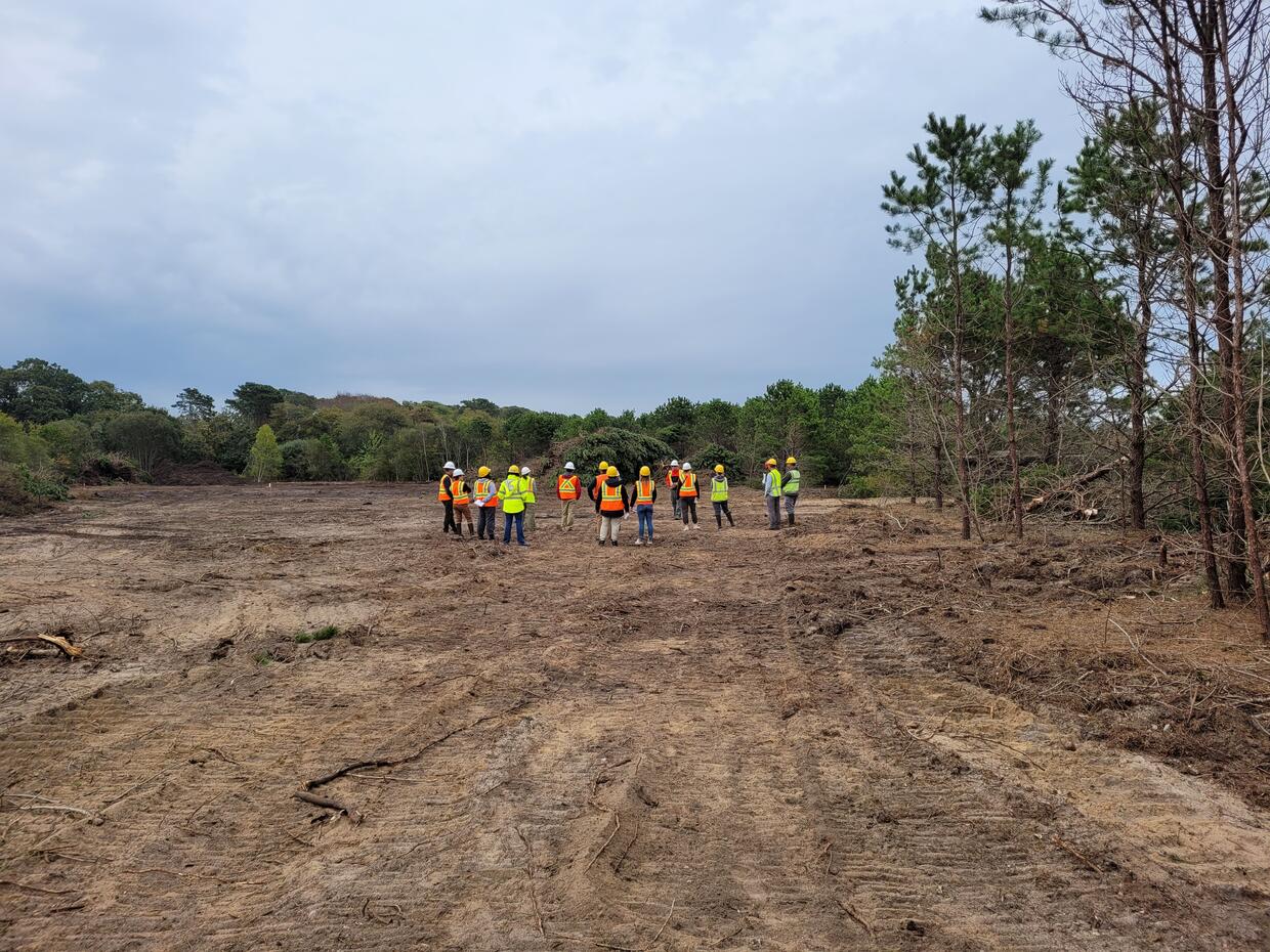 A group of people with hard hats and high visibility vests standing at the Cold Brook Restoration site.