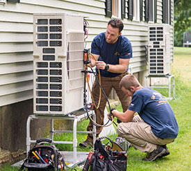 two men fixing a heat pump