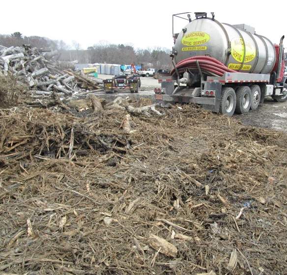 Septic truck backed up to the shredded wood waste pile.