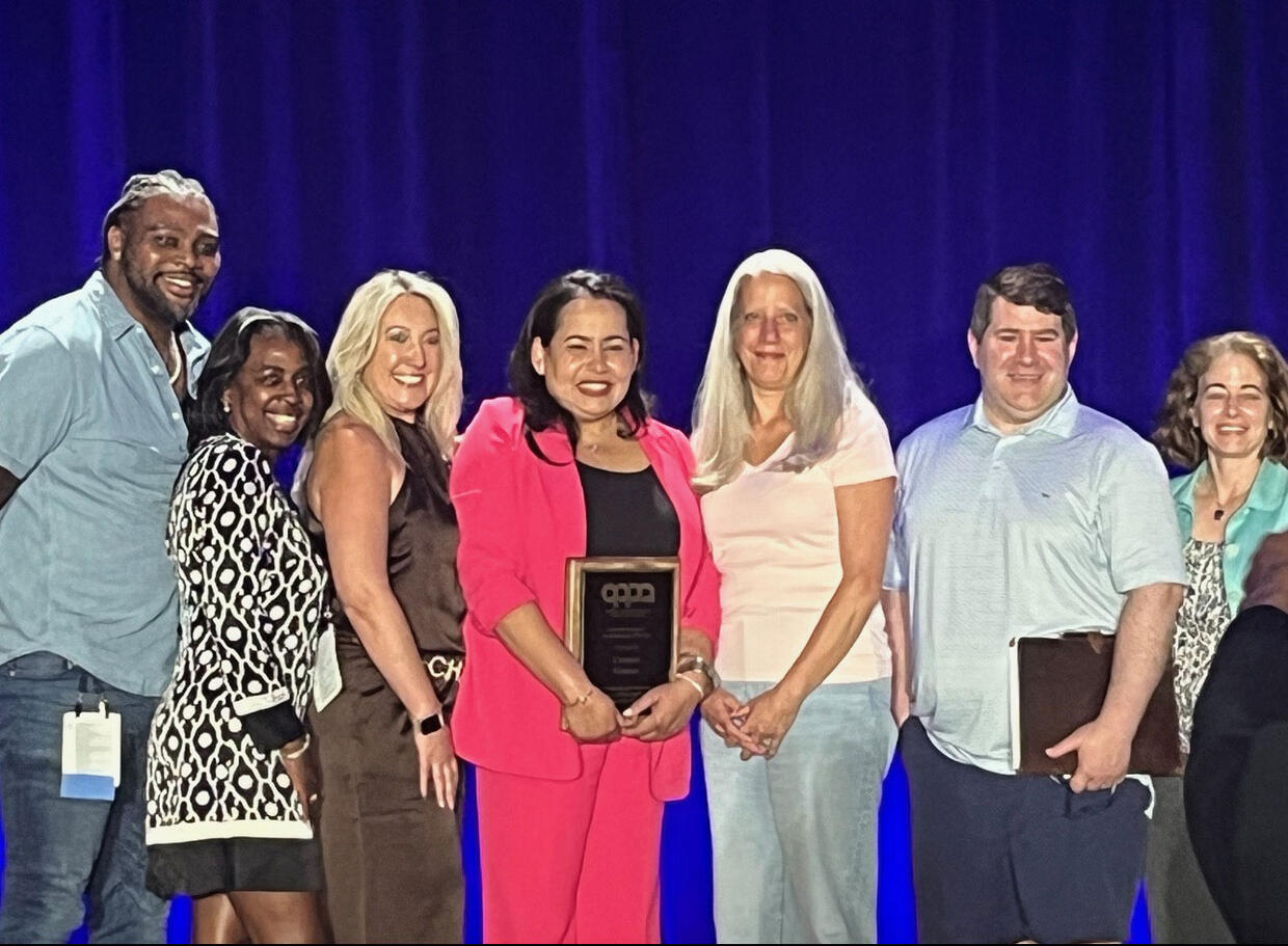 Dr. Carmen Gomez holding her award and standing with her colleagues