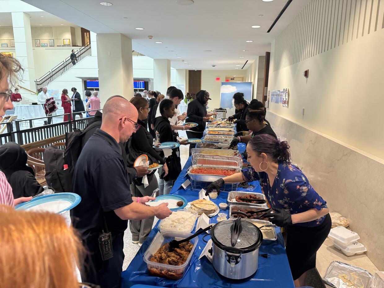 A long table covered in various foods with people serving others on the other side.