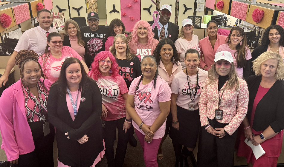 A large group of people wearing pink pose for a picture.