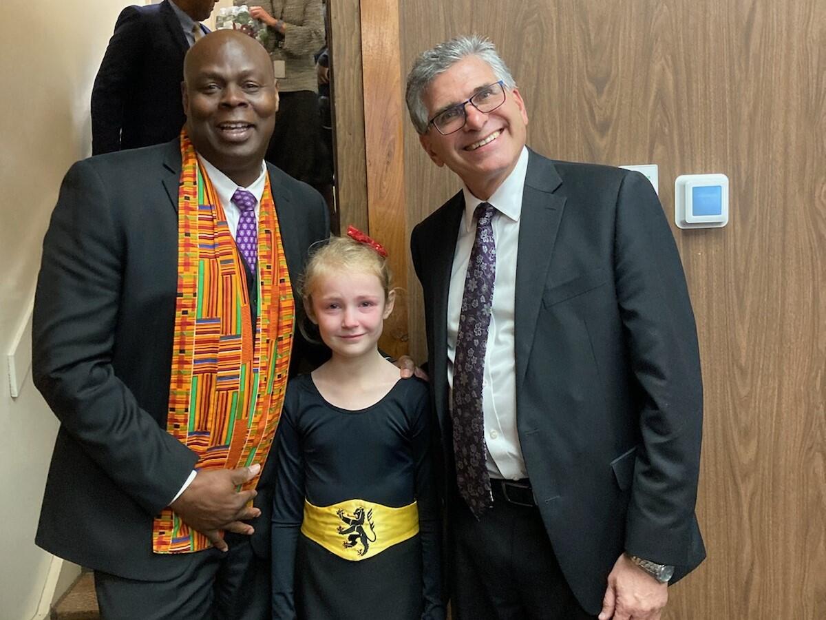 Two men pose with a young Irish step dancer