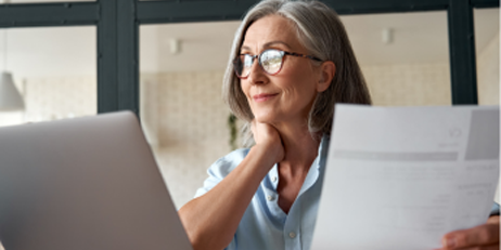 Smiling mature middle aged business woman using laptop working on computer sitting at desk