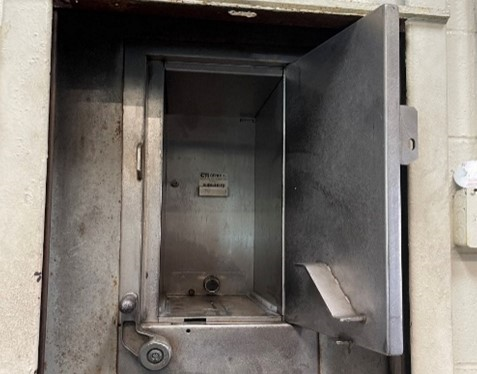 This image shows the inside of the passthrough to the wall-mounted vault in which cash from fare payments is held until it is counted.