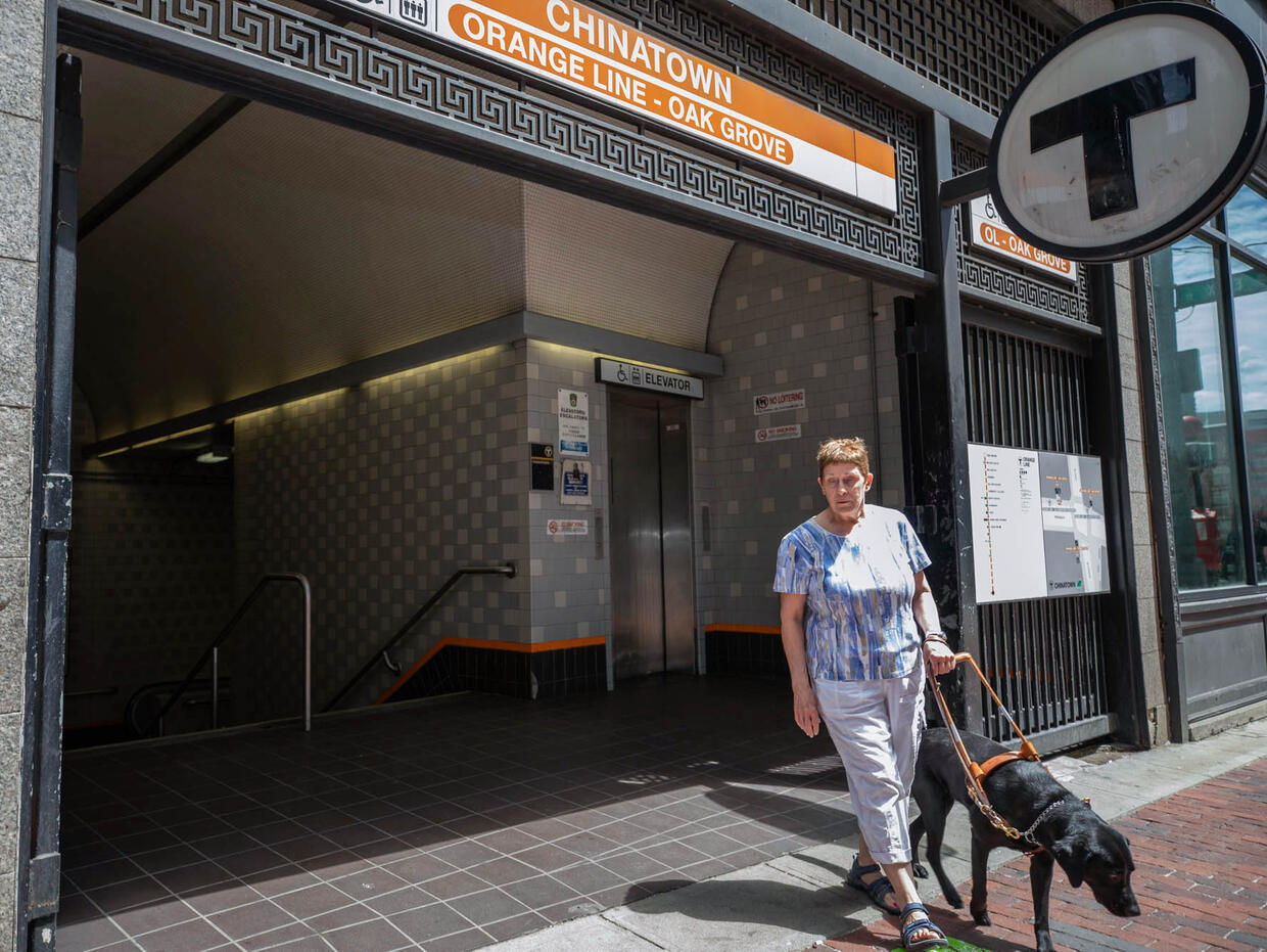 Woman exiting Chinatown MBTA station with guide dog