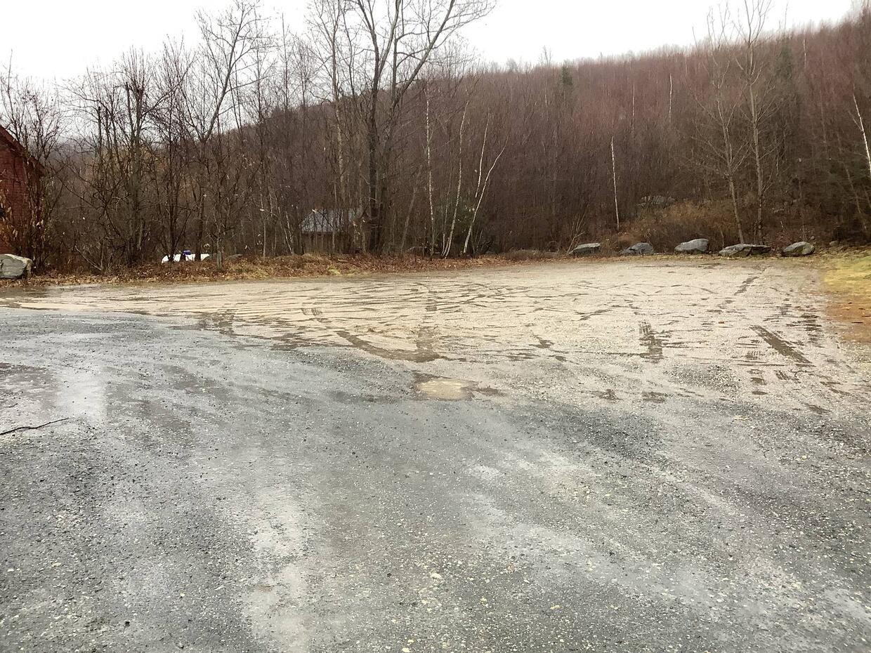 A small, flat gravel parking area. There are no cars parked.