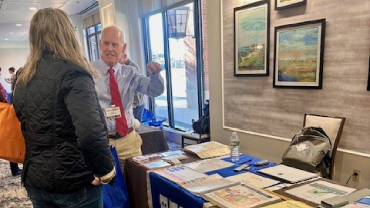 Attendee talking to Brian Mc Donald at the National Braille Press exhibitor table