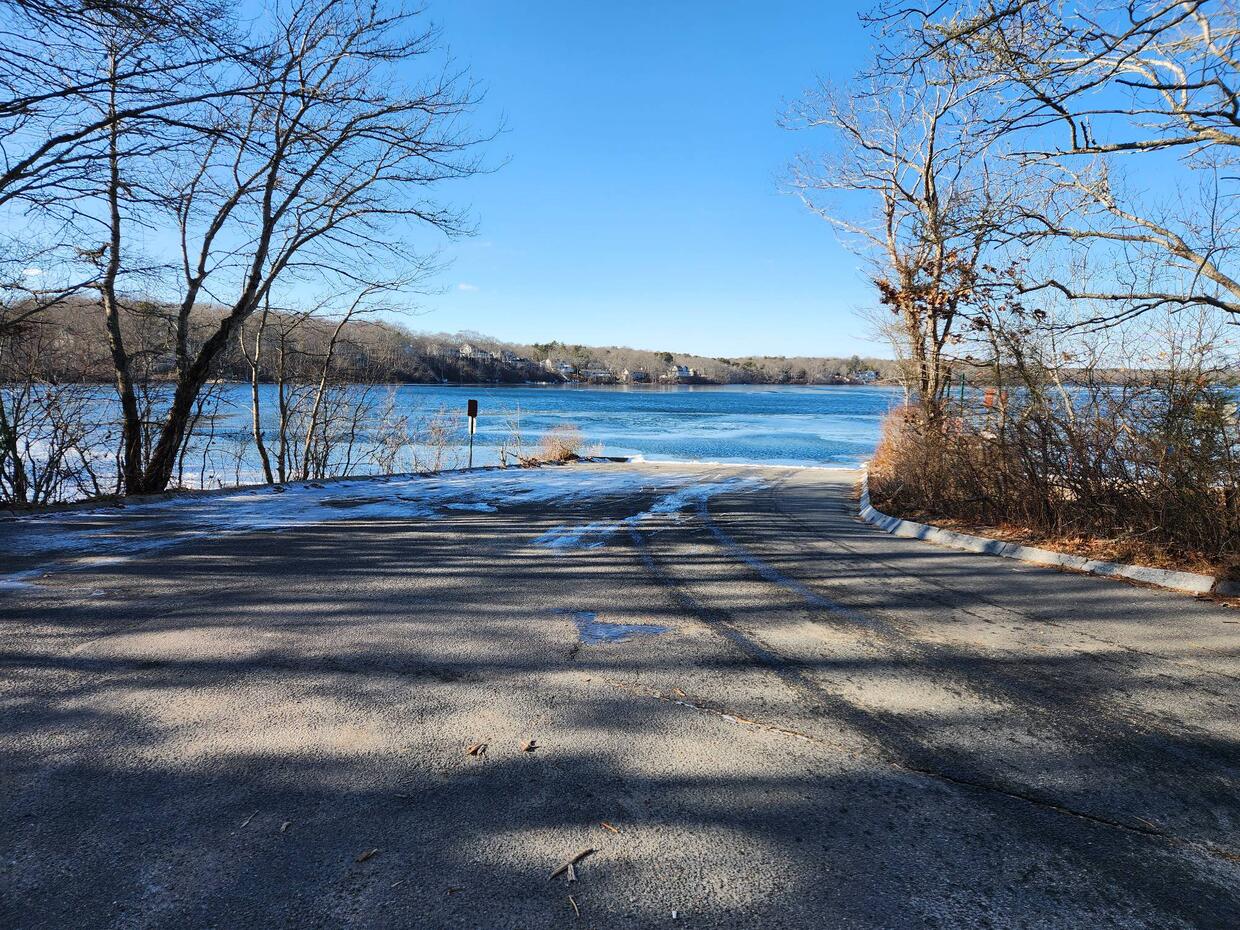 Mashpee Wakeby Pond from the boat ramp on a clear sunny day. The water is partially frozen.