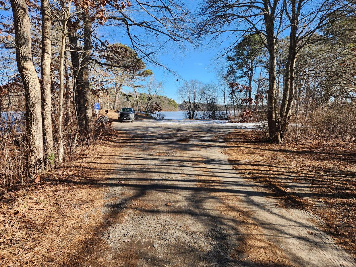A small, unpaved parking area by the water with one car parked