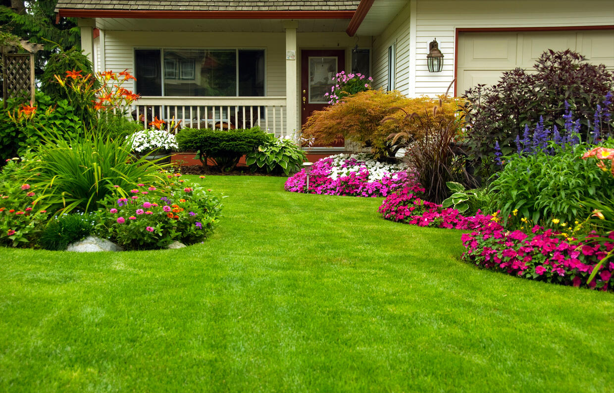 House with landscaped front yard of lawn, shrubs, flowers, and trees