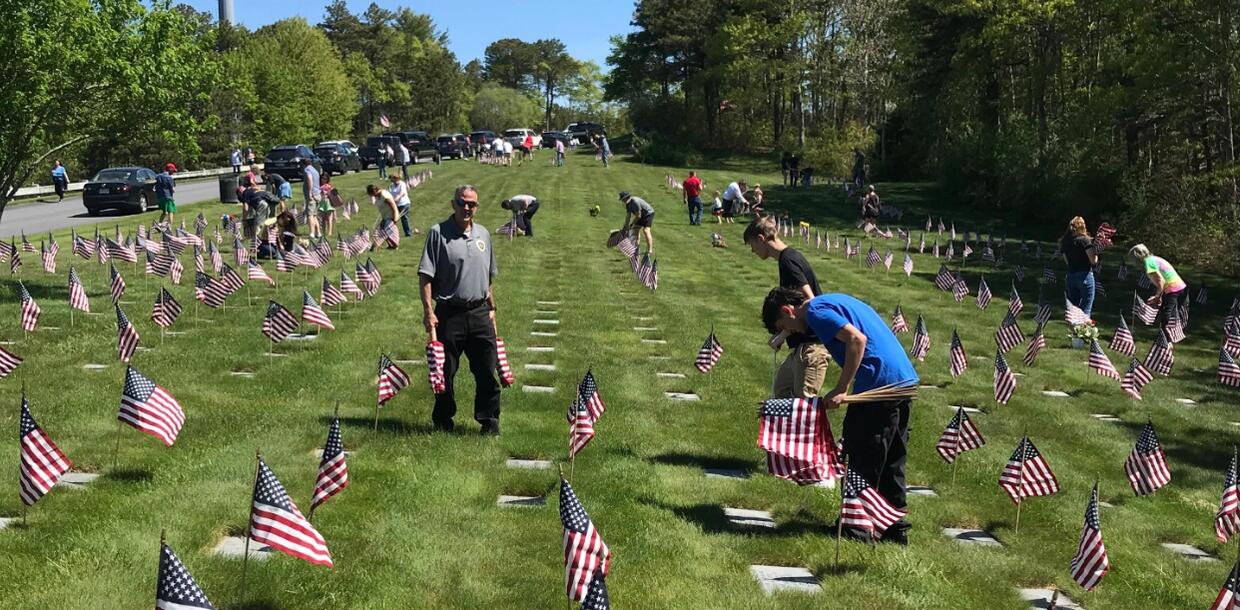 Volunteers setting up flags at the grave sites of veterans. 