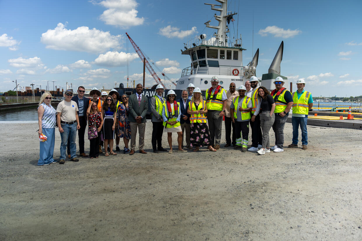 Group photo standing behind a tug boat. 
