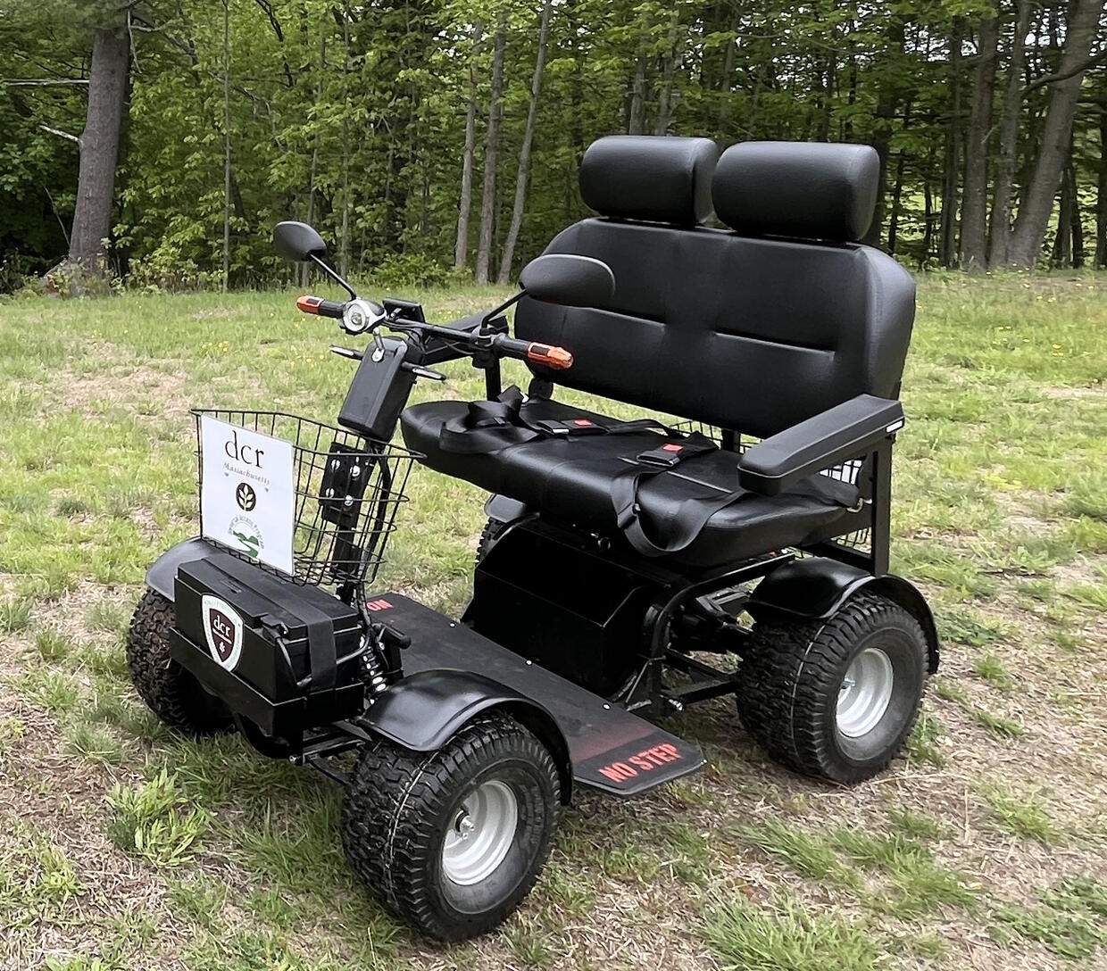 An electric scooter with 4 large tires and a double-wide seat.