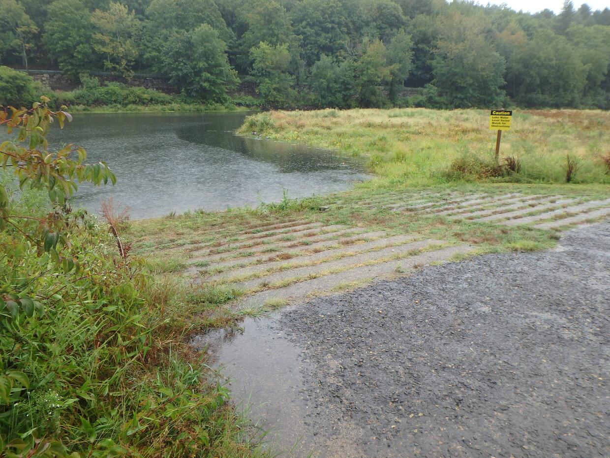 The lake from a wide concrete boat ramp that is slightly overgrown