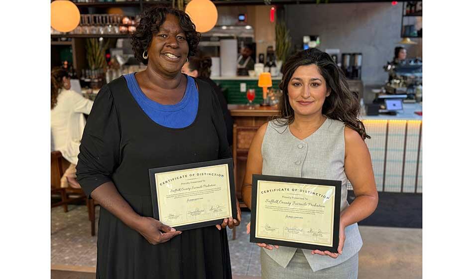 Two women holding certificates and standing in a casual restaurant setting