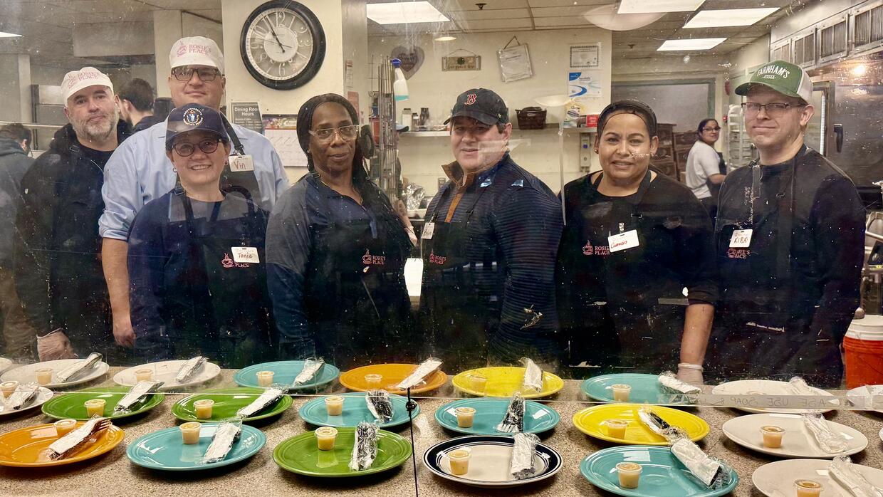 Seven people pose together in matching aprons. 