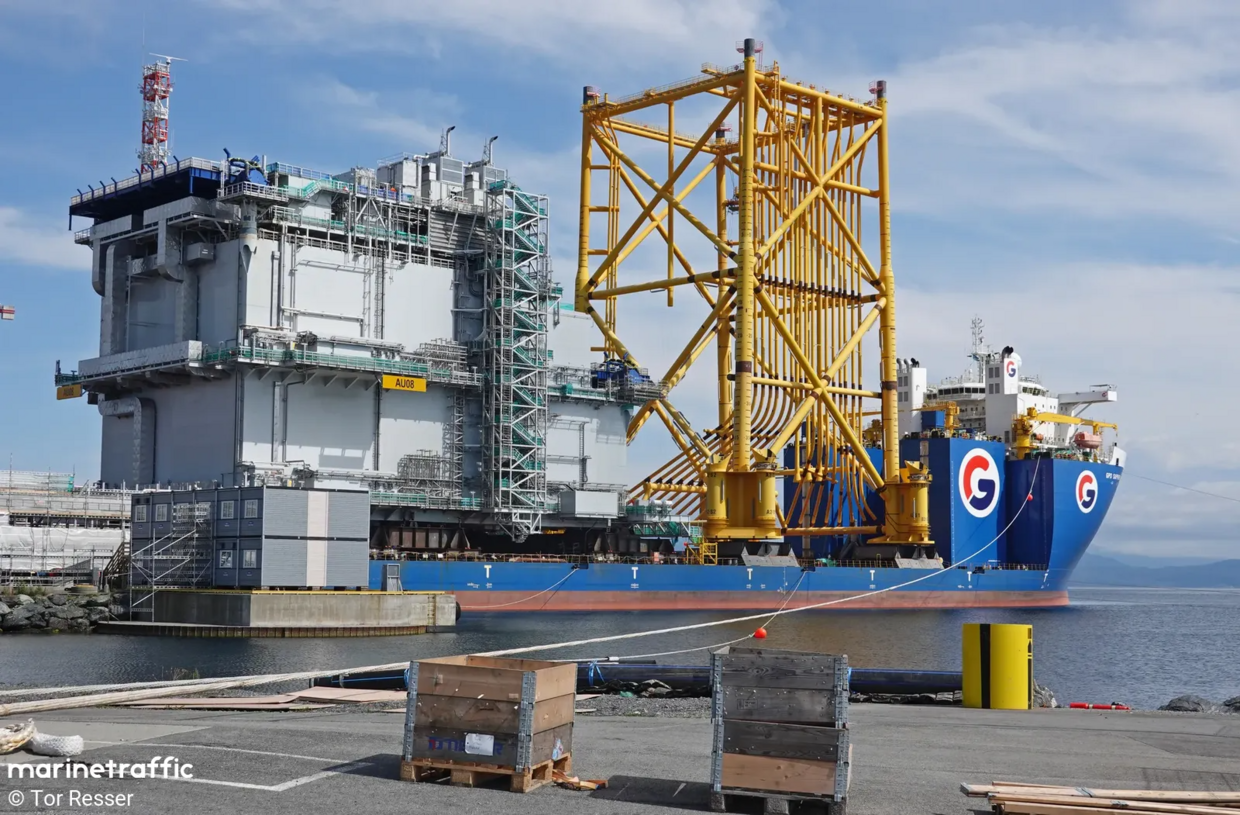 Large ship carries tall yellow jacket foundation and large grey substation. 