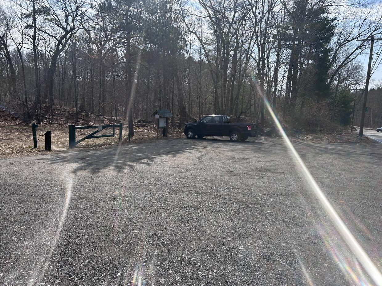 gravel parking lot at trail head into brewer brook reservoir lands with gate