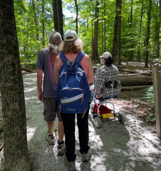 Three users on a crushed stone trail, one using an assistive device.