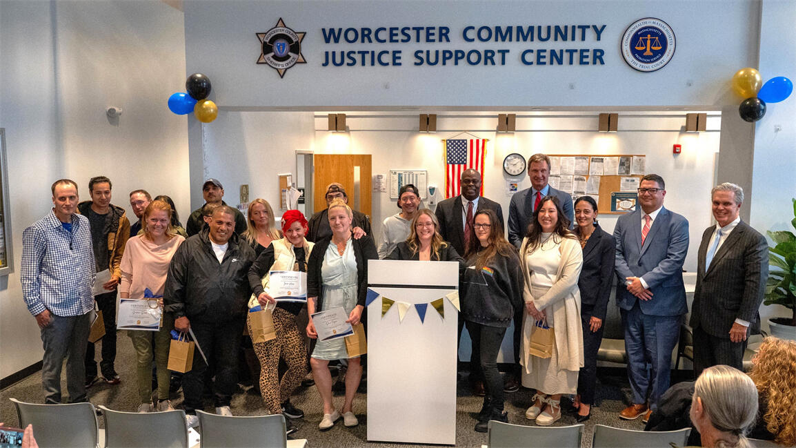 A large group pose together at a Worcester Community Justice Support Center ceremony 