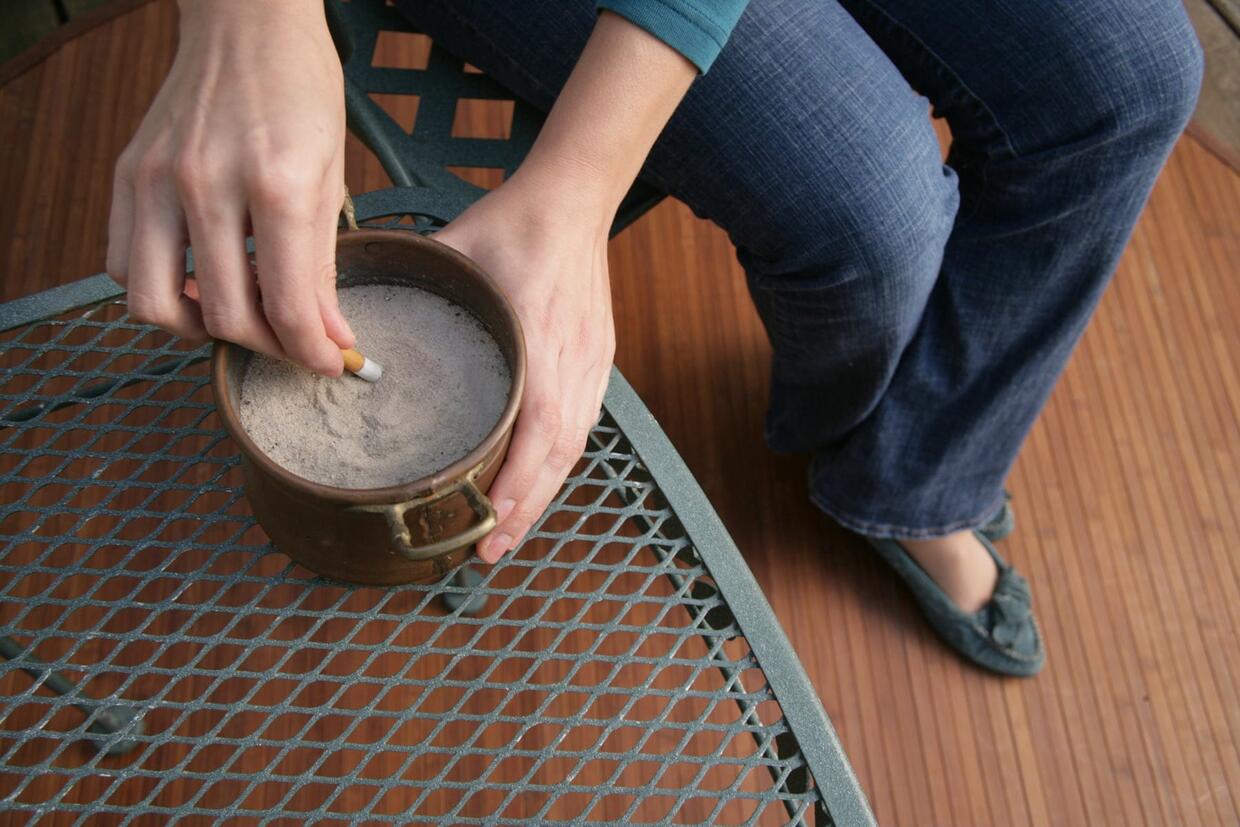 Putting a cigarette out in a pail with sand.