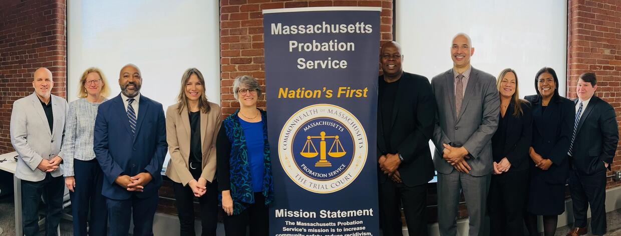 Ten people pose together next to a Massachusetts Probation Service pop-up banner.