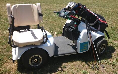 Soloride cart on a golf green with its seat to the side and golf clubs mounted in front. 