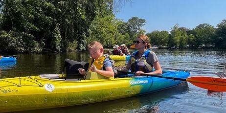 Children and adults kayaking on a river.