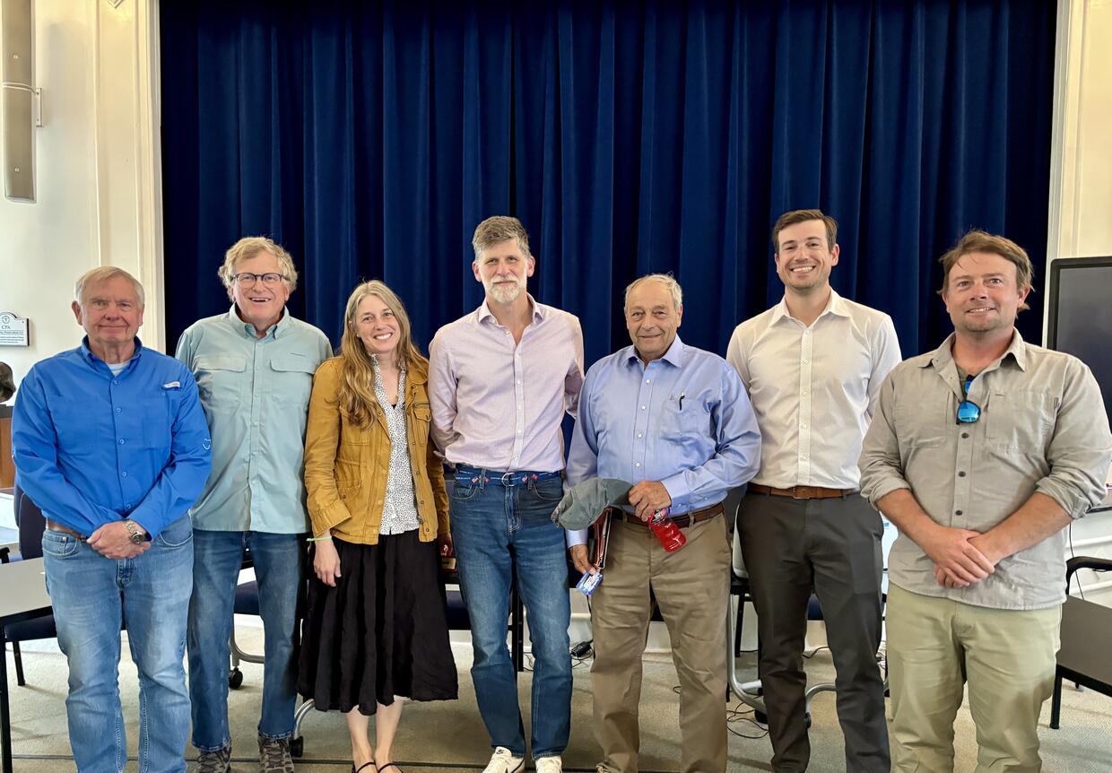 Seven people stand together smiling. 