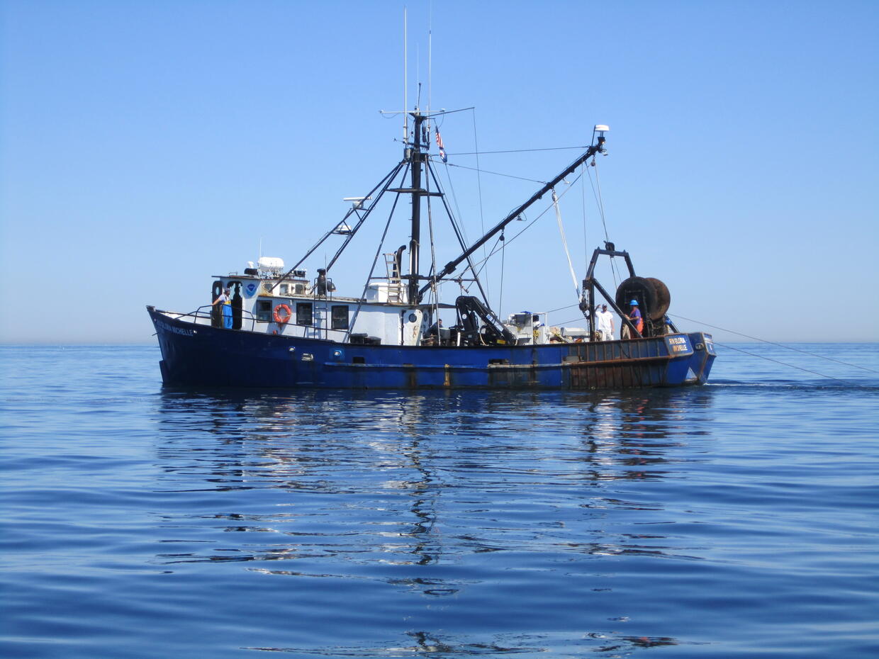 Blue and white fishing vessel in water. 
