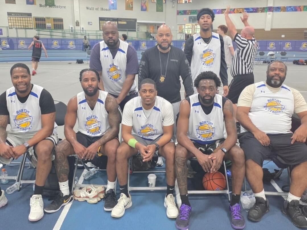 Eight men pose together in matching basketball jerseys