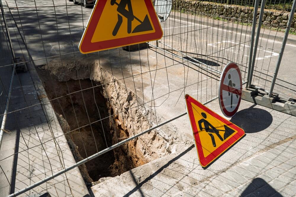 Open trench with caution road signs.