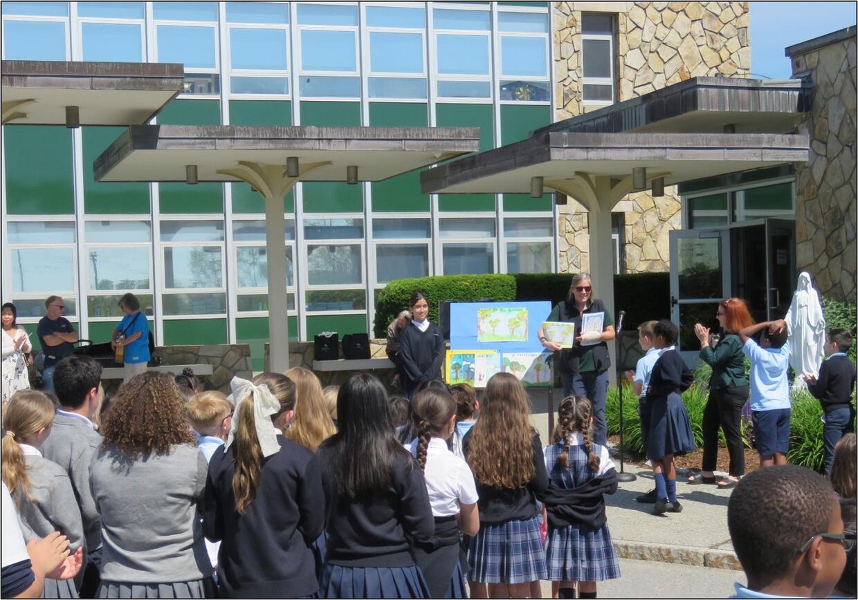 DCR Urban and Community Forestry Coordinator Julie Coop presents the 2026 contest award to Rylee B. at St. Bernard's Elementary School in Fitchburg.