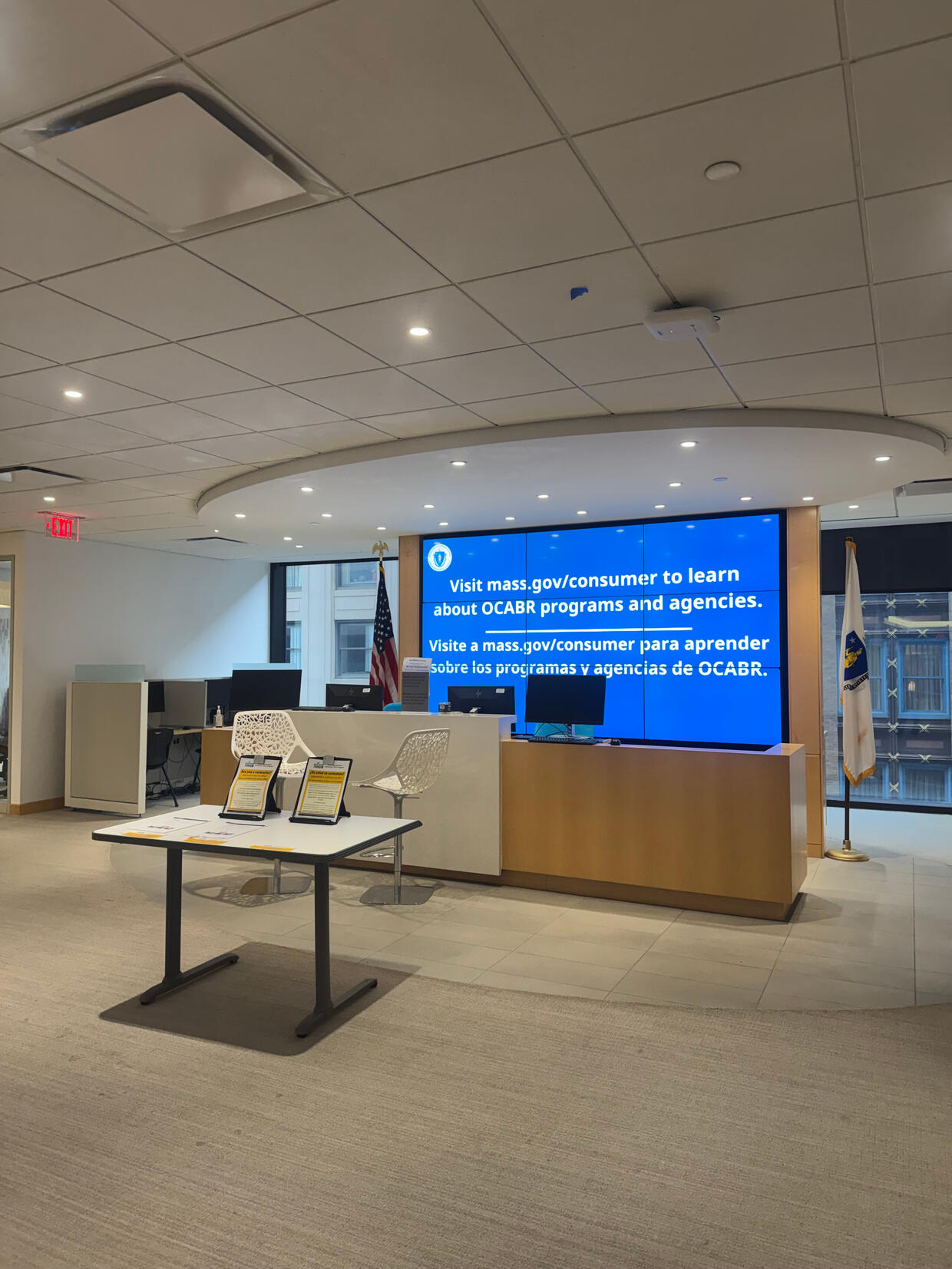 An office lobby with a digital screen displaying information about OCABR programs and agencies.