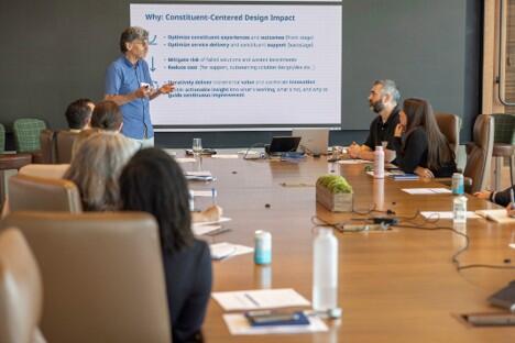A group of EOTSS employees sit at a conference table discussing the Constituent Experience Center of Excellence
