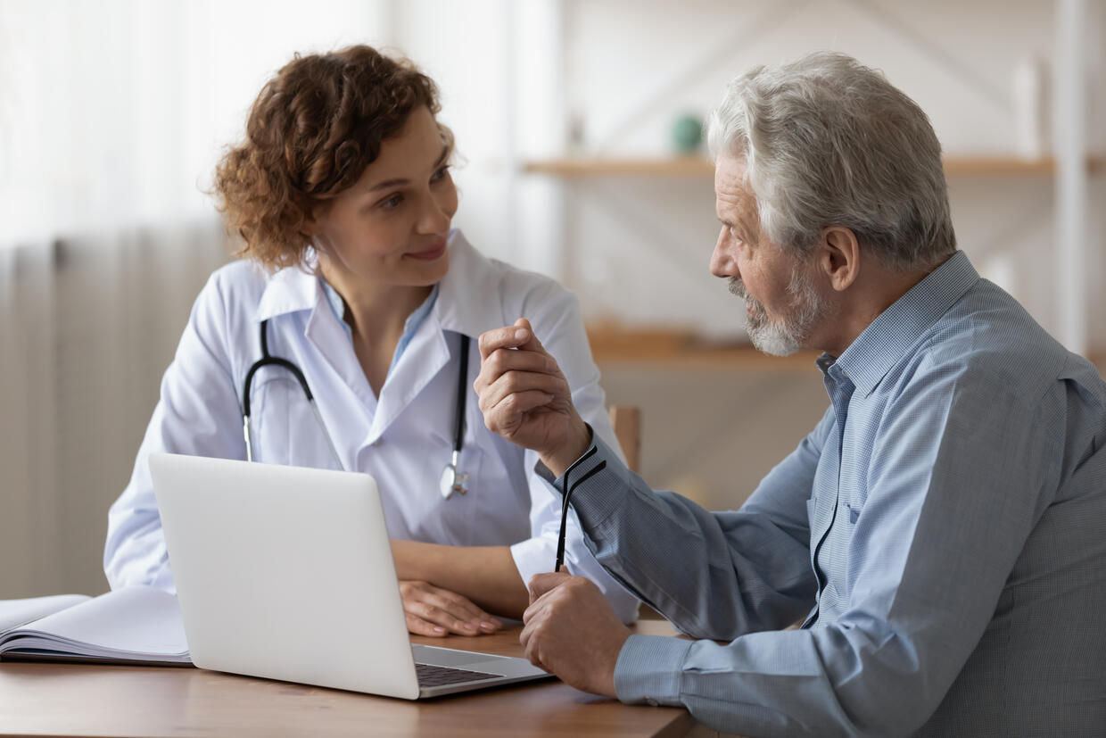 Female clinician is listening to a male patient talk.