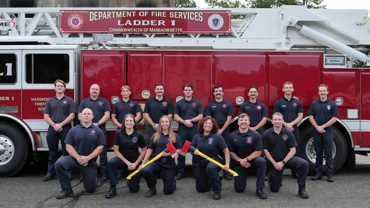 15 new firefighters in front of a ladder truck