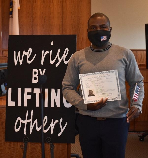 New American citizen stands with his certificate and American Flag at ceremony