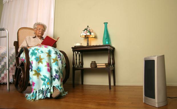 Older woman with space heater safely 3-feet away