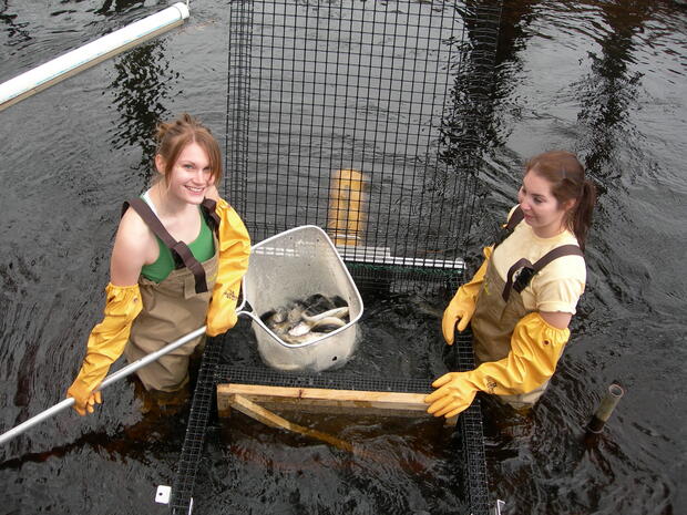 Two women smile as the conduct a water sampling activity
