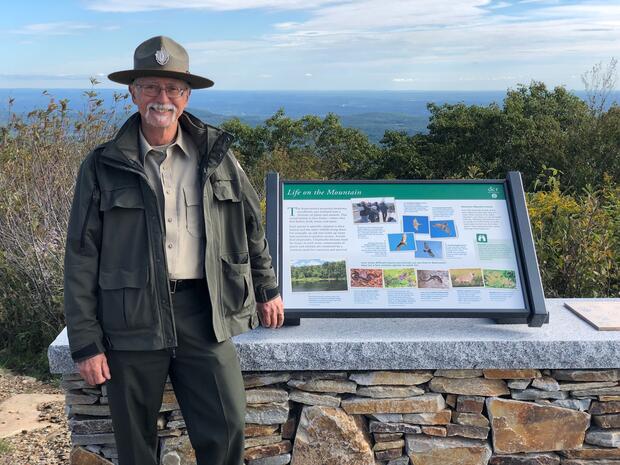 park ranger by sign in mountains