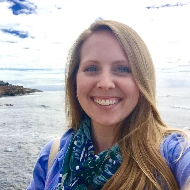 Krista standing in front of the ocean and smiling at the camera.