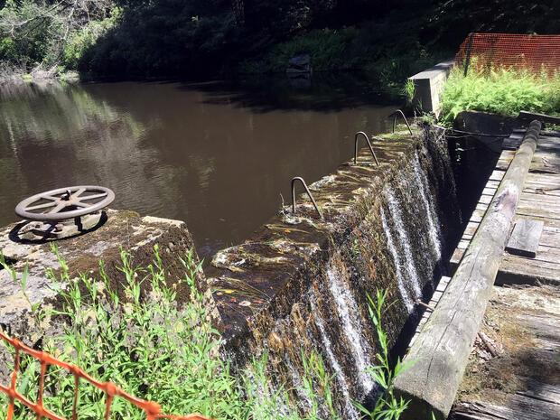 Water flowing over a concrete dam.