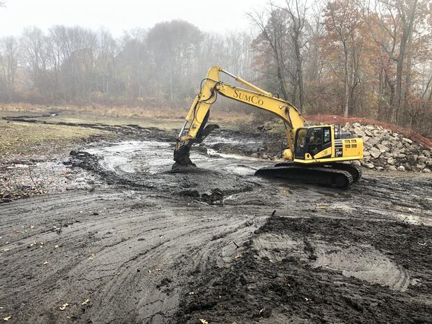 A backhoe operating on a muddy hill.