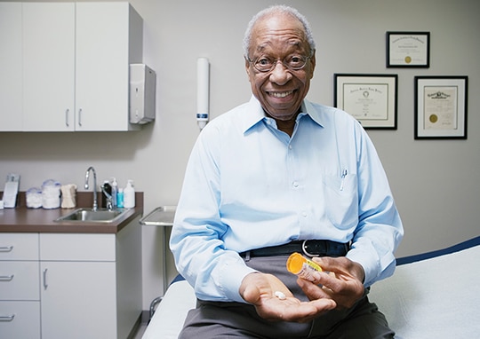 senior man in a doctor's office holding his medication